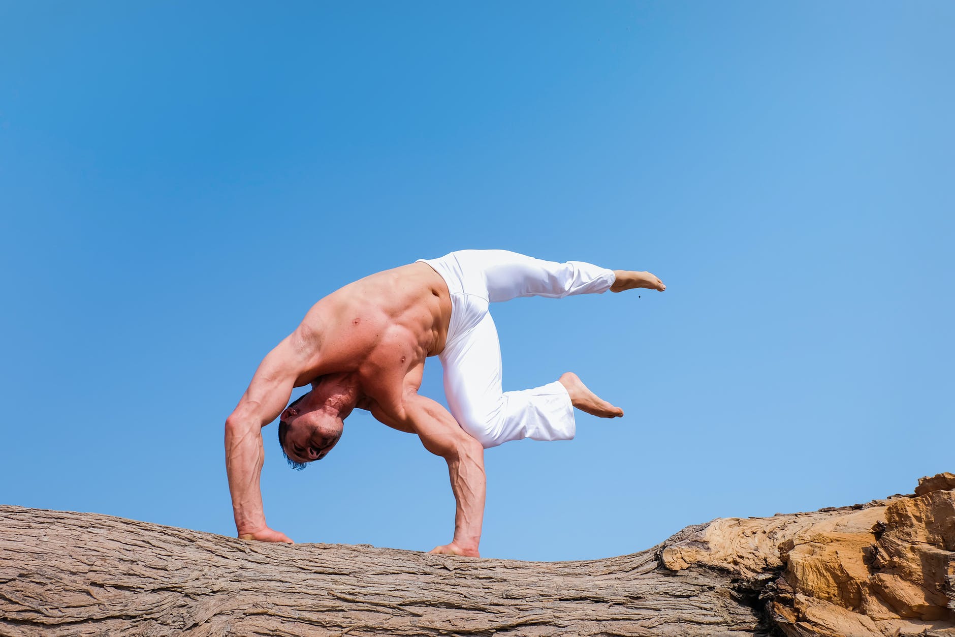 man in white pants doing calisthenics flag